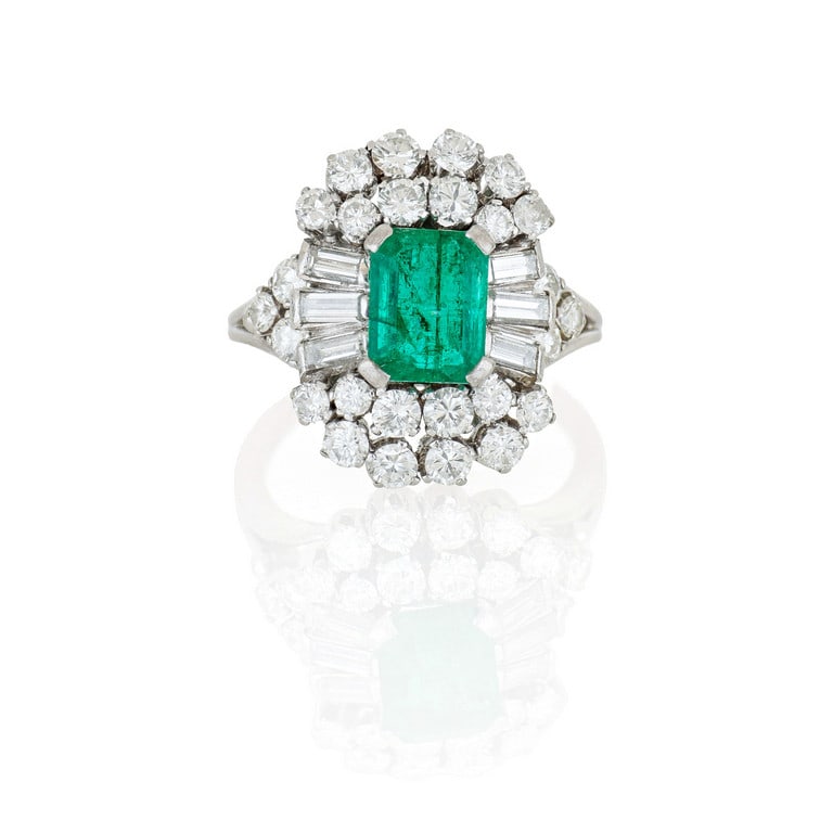 Anello in platino con smeraldo, al centro una: Anello in platino con smeraldo, al centro una gemma taglio rettangolare di ct. 1,40 ca., ai lati diamanti taglio brillante e baguette, per ct. 1,20 ca., a formare un doppio contorno, con due ventaglie