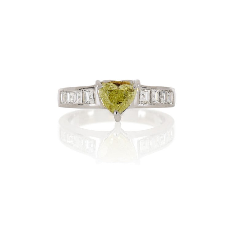 Anello in oro bianco con diamante taglio cuore di: Anello in oro bianco con diamante taglio cuore di colore fancy yellow, ct. 0,70 ca., ai lati sul gambo altri 8 taglio carrè per ct. 0,50 ca. Misura n. 9. Peso 4,77 g.