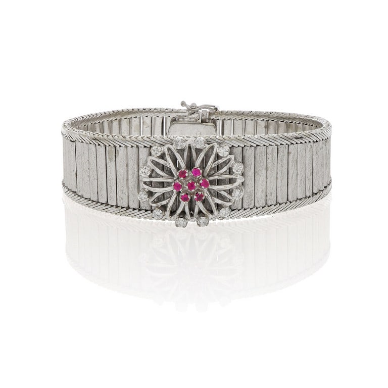 Bracciale in oro bianco a settori snodati e: Bracciale in oro bianco a settori snodati e scalati, al centro un rosone con piccoli diamanti e rubini. Dimensioni 19 x 2 cm. Peso 57,0 g.