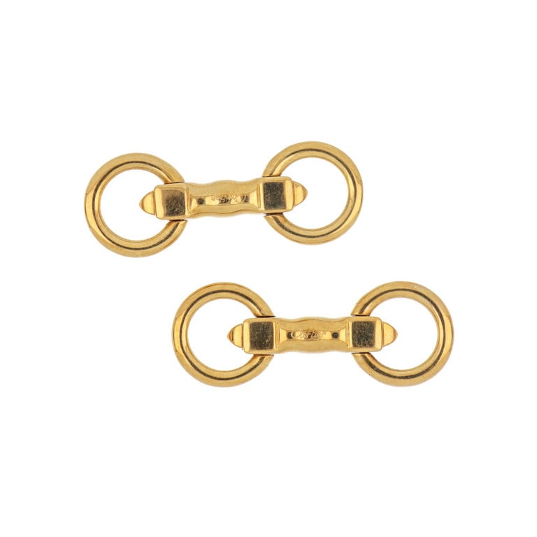 CARTIER - Gemelli in oro giallo a staffe rotonde: CARTIER - Gemelli in oro giallo a staffe rotonde contrapposte, in perfette condizioni di conservazione. Timbri, firma e numeri nella losanga centrale, 3,5 x 1,3 cm da aperti. Peso 11,78 g.