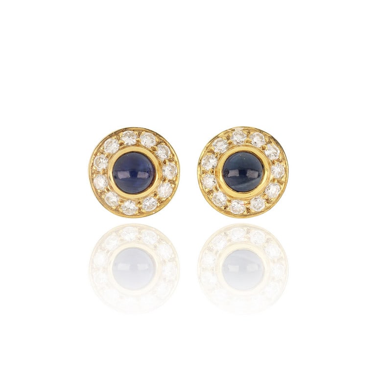 CARTIER - Orecchini a clips di forma rotonda in: CARTIER - Orecchini a clips di forma rotonda in oro giallo, l'elegante manifattura è adornata con due zaffiri taglio cabochon al centro e un contorno di 22 piccoli diamanti taglio brillante per c