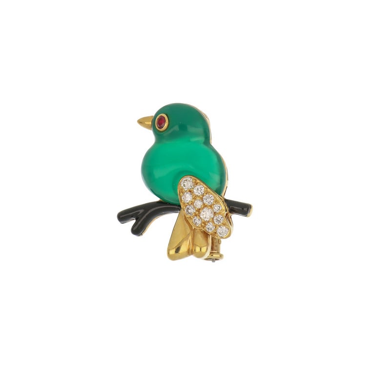 CARTIER - Deliziosa spilla in oro giallo e pietre: CARTIER - Deliziosa spilla in oro giallo e pietre preziose, un simpatico uccellino su ramo di onice, realizzato con corpo di crisoprasio verde e ali in pavè di piccoli diamanti, ci osserva. La fi