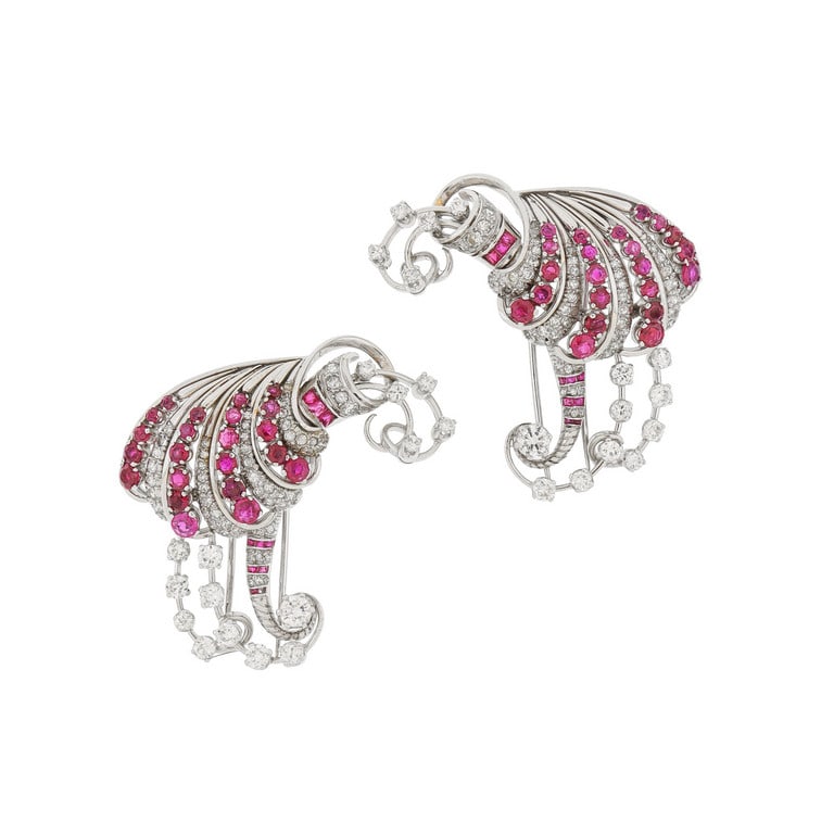 Coppia di spille speculari anni 50 in platino, di: Coppia di spille speculari anni 50 in platino, di bel motivo a volute tempestate di rubini di ottima qualità e diamanti per stimati 4 ct circa. Peso 62,27 g.