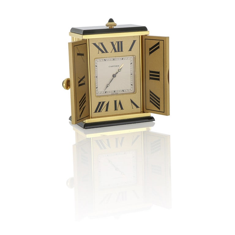 CARTIER - Pendoletta da viaggio di forma: CARTIER - Pendoletta da viaggio di forma rettangolare, realizzata in metallo dorato e onice, animata da movimento elettromeccanico, il quadrante a numeri romani si cela dietro un siparietto a due ante