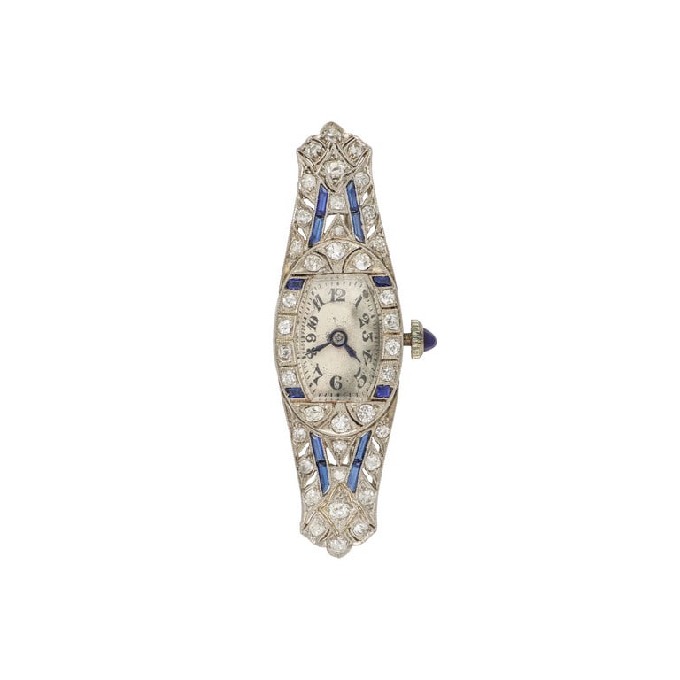 Spilla orologio in platino, primi '900, la forma: Spilla orologio in platino, primi '900, la forma tonneau leggermente curva è adornata con piccoli zaffiri e diamanti taglio antico, l'orologio funzionante è a carica manuale, si consiglia re