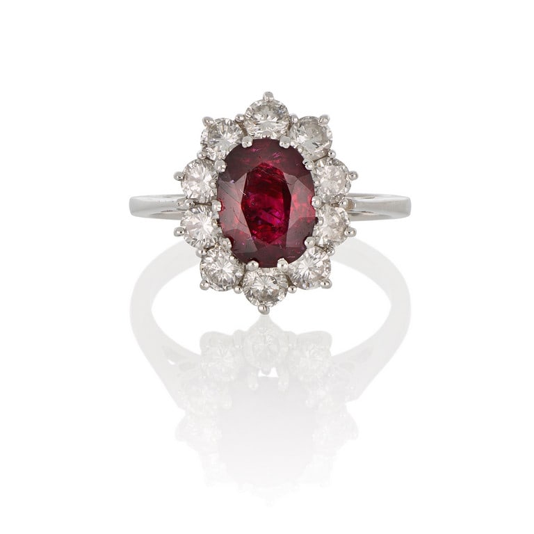 anello: Elegante anello a margherita in oro bianco, al centro un rubino rosso intenso di ct. 1,40 ca. contornato da 10 diamanti taglio brillante per ct. 1,0 ca. Misura n. 7. Peso 4,1 g.