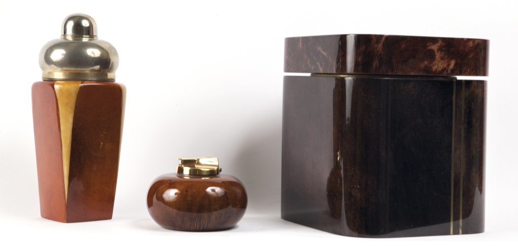 TURA Uno shaker, un accendisigari, un: TURA Uno shaker, un accendisigari, un secchiello portaghiaccio. Anni '70. Shaker (legno rivestito in pergamena colorata e rifinita in poliestere e metallo): altezza cm 23 accendisigari (legno rivestit