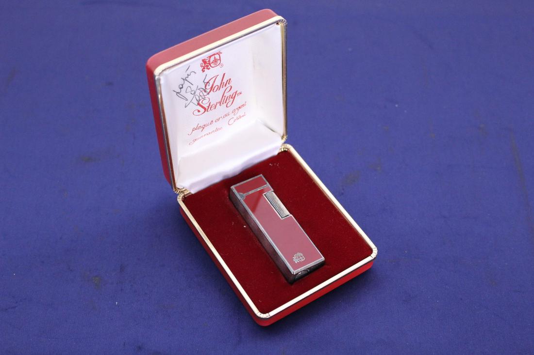 John Sterling, Gold and Silver Plate Lighter in Red Box: John Sterling, Unused Gold and Silver Plated Lighter in Red Box. Box measures 2.75" x 3.3" x 1". Lighter measures 2.5" x 0.75" x 0.60"Thick.