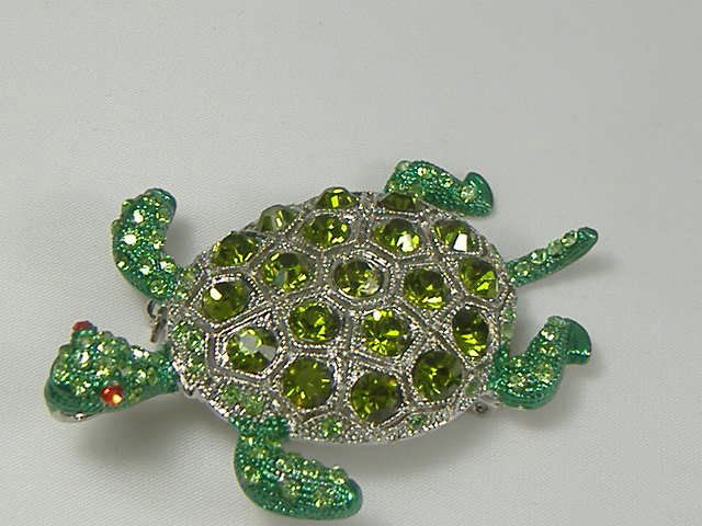 Emerald Swarovski Crystal Turtle Pin/Brooch: For auction, a superb turtle pin/brooch featuring emerald swarovski crystals. It also features a ruby colored crystal for the eyes and the shell has a silver tone underlay. The pin measures approx. 2