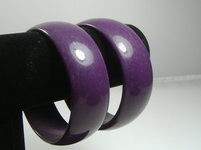 2 Vintage Lucite 1970s Deep Amethyst Bangle Bracelets: Manufactured by Best Plastics of Providence RI in the 1970s. Original factory stock. Each bracelet measures approx. 1 inch in width and approx. 2 3/4 at their maximum diameter.