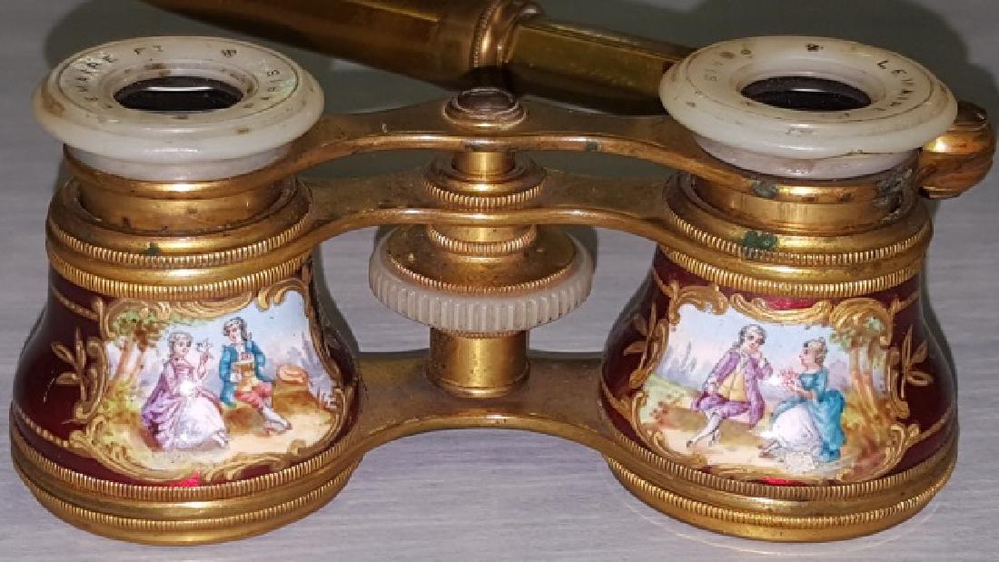 *PAIR OF ENAMEL OPERA GLASSES: Enamel and brass lorgnette, body having red enamel ground with gilt highlights and handpainted garden scenes with lovers, mother-of-pearl eye cups marked "Lemaire Ft Paris", with brass telescopic hand