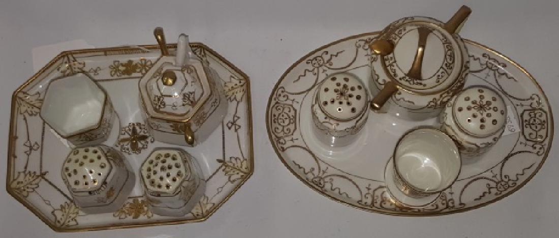 *2 NIPPON PORCELAIN CONDIMENT SETS: Each with tray, covered sugar with spoons, toothpick, and pair of shakers, both with gilt floral and scroll decoration.