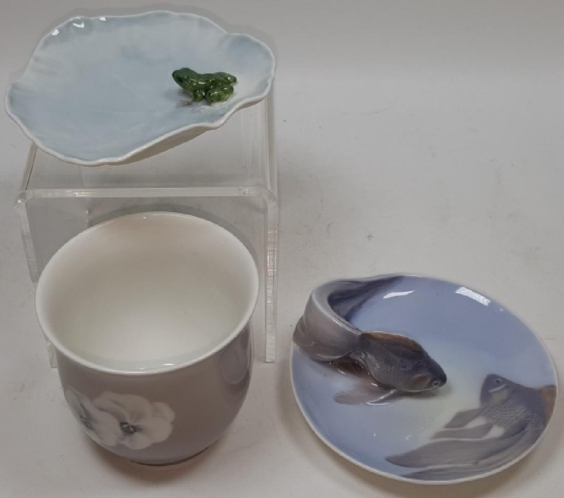 *3 PIECES PORCELAIN: Bing & Grondahl cup #8569-601B, 1-L, approximate height 3 1/2", and 2 Royal Copenhagen trays, #2477 decorated with frog, length 4 1/4", and #931 decorated with goldfish, length 5".