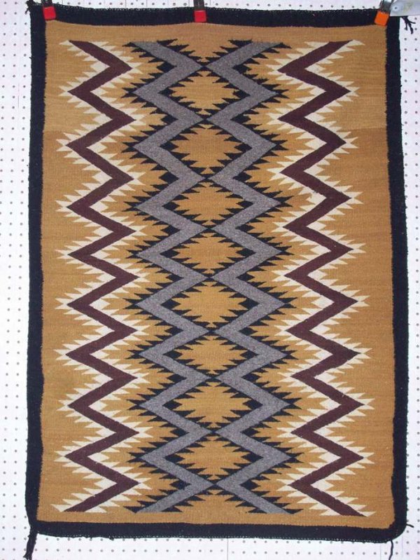 ***NAVAJO WEAVING: Having serrated zigzag line design in colors of gold, black, brown, grey, and white, approximate size 48" x 34".