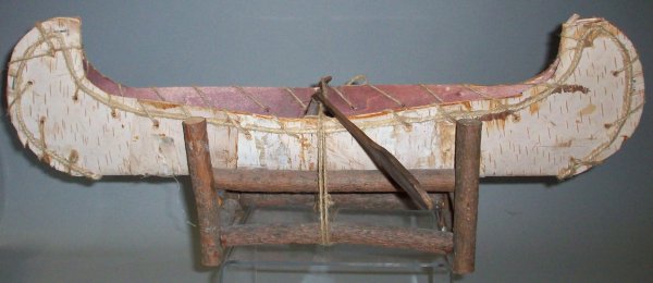 BIRCH BARK CANOE: With wood stand and 2 paddles, approximate length 22".