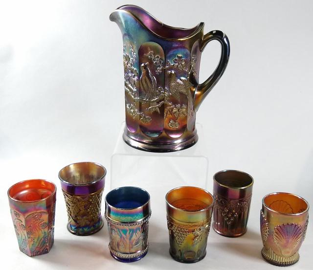 7 PIECES CARNIVAL GLASS BEVERAGE SET: 7 pieces amethyst carnival glass, pitcher "Singing Birds" pattern, along with 6 misc. tumblers, including grape leaf, shell, butterfly, etc., pitcher and grape leaf tumbler marked N (Northwood)