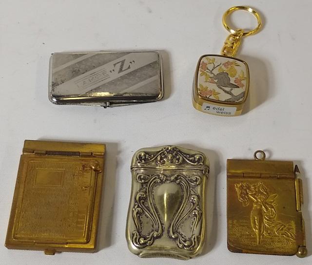 GROUP: 2 match cases, 1 silver, 2 writing cases, and a wind-up charm keychain.