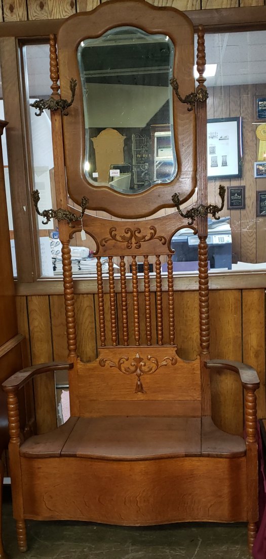 VICTORIAN OAK HALL TREE: Having shaped mirror over 4 hooks, with curved arms centered by hinged seat, opening to storage area, raised on spool turned supports, approximate height 85 1/2", width 39 1/2", depth 17 1/2".