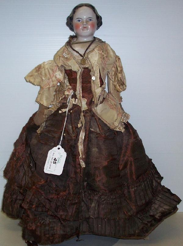 CHINA HEAD DOLL: Having blue eyes and black hair, on cloth body with sewn boots, comes from the estate of Geraldine (Jerrie) Kneipper, Kenosha, WI, member of ''The Badger State Doll Club'', approximate height 16''.