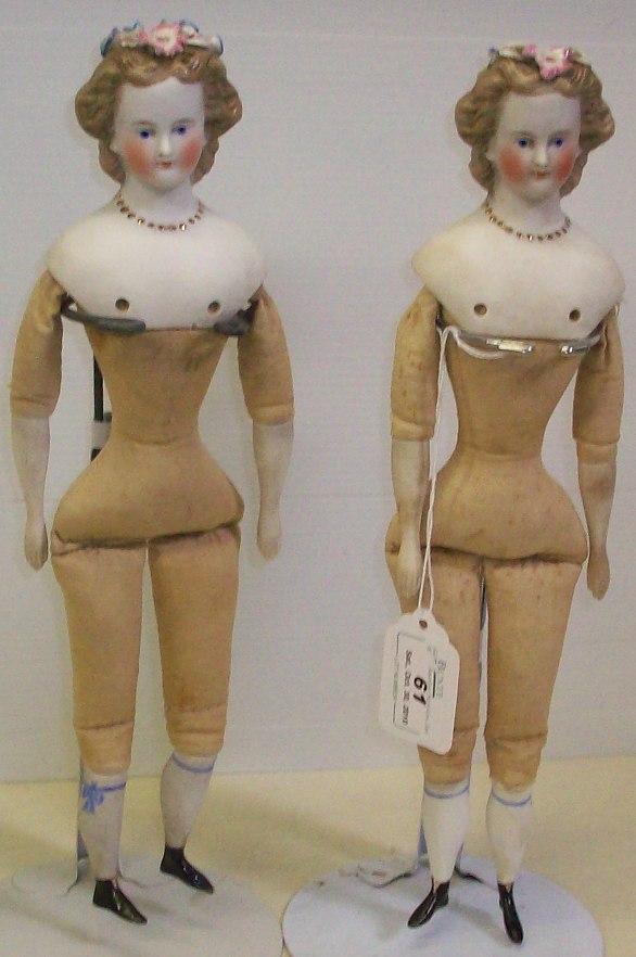 PAIR OF BISQUE HEAD DOLLS: Twins, each having blue eyes and brown hair, flowers in hair, molded gold necklace, on cloth bodies with bisque half-arms and legs with painted boots, having receipt for $1,300, comes from the estate 