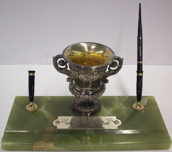 ***PRESENTATION PEN STAND: Having silverplate urn with plaque, ''To Arch Ward 20th Anniversary All Star Football Classic From Sugar Bowlers 1933-1953'', raised on onyx marble plinth.