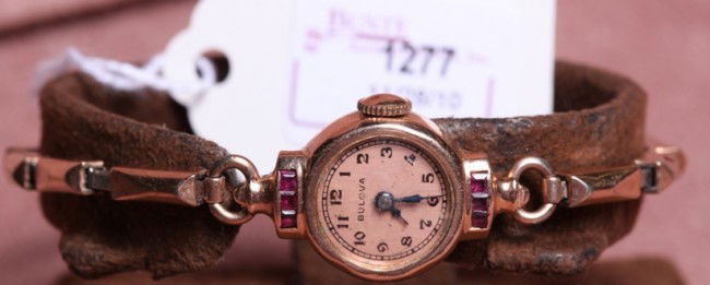 ***LADY'S BULOVA 14K ROSE GOLD WRISTWATCH: Having jeweled movements, stem wound and set, with Arabic numeral markers on champagne finish dial, contained in 14K rose gold and ruby set case, fitted with 14K rose gold plated strap.