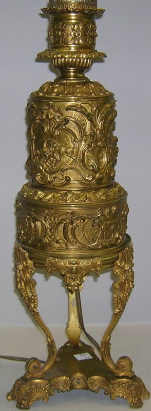 ***BRASS TABLE LAMP: With relief decoration depicting scrollwork, fighting dogs, shells, etc., approximate height 27''.