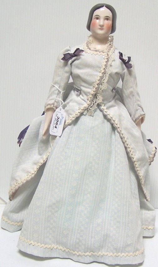 ***CONTEMPORARY CHINA HEAD DOLL: Having black straight hair, painted features, on cloth body with porcelain arms and legs and painted laced boots, marked on back indistinctly, approximate height 16''.
