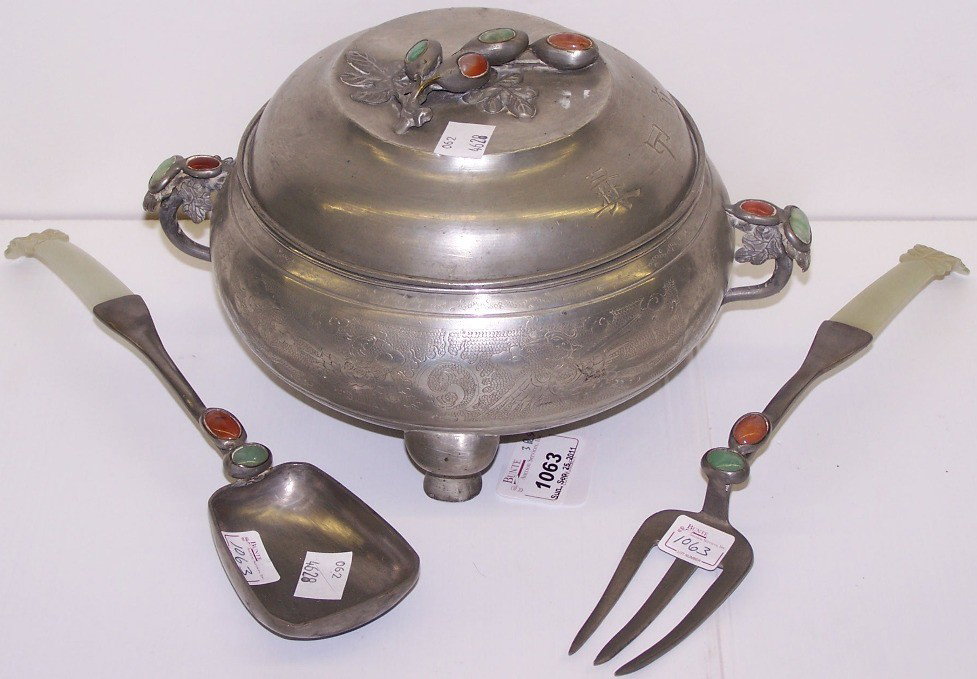 ***THREE PIECES OF CHINESE PEWTER: Comprising pewter covered pot with jade and carnelian inlaid stones, together with pewter serving fork and spoon, both having jade and carnelian inlaid stones and fitted with green jade handles.