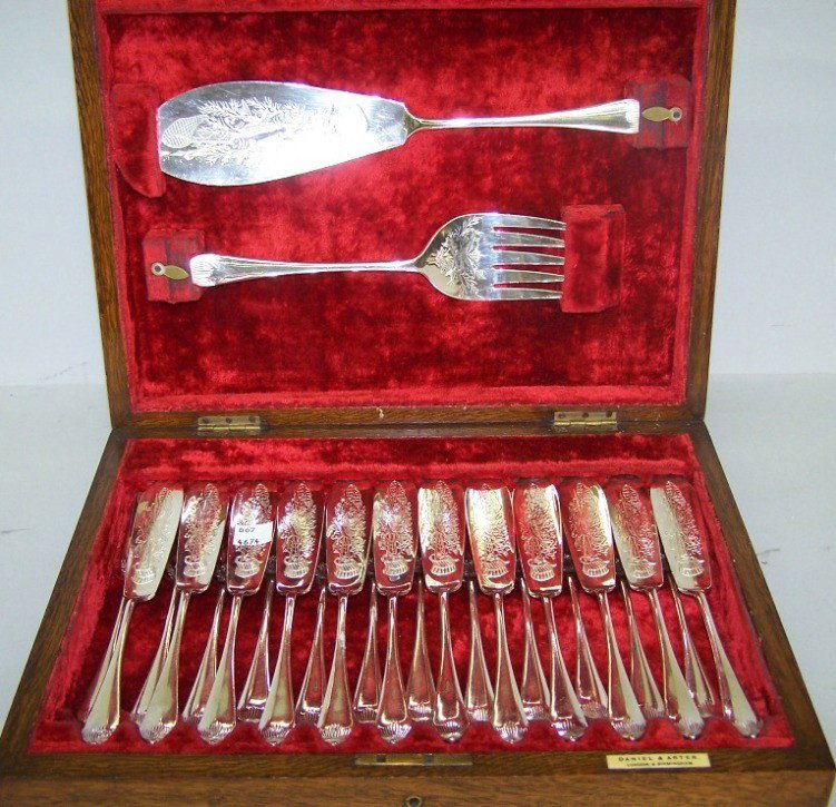 ***ENGLISH SILVERPLATE FISH SET: ***ENGLISH SILVERPLATE FISH SET| By Daniel and Arter, 12 forks, 12 knives and serving fork and knife, enclosed in oak case, interior marked with label "Daniel and Arter London & Birmingham"