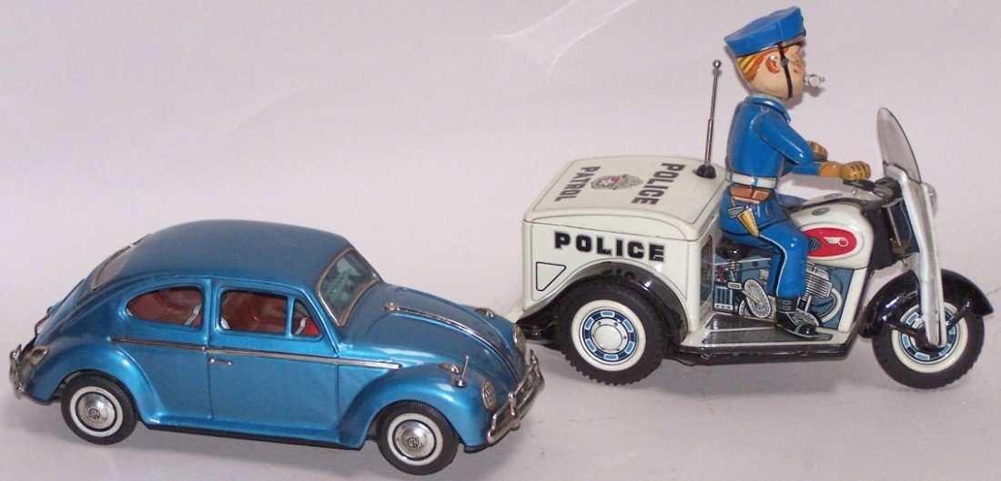 ***2 BATTERY OPERATED TIN VEHICLES: Volkswagen Beetle, made in Japan by Bandai, approximate length 11'', and police patrol three-wheeled motorcycle with rider, marked ''T.N. (Toy Nomura), length 9 1/2''.