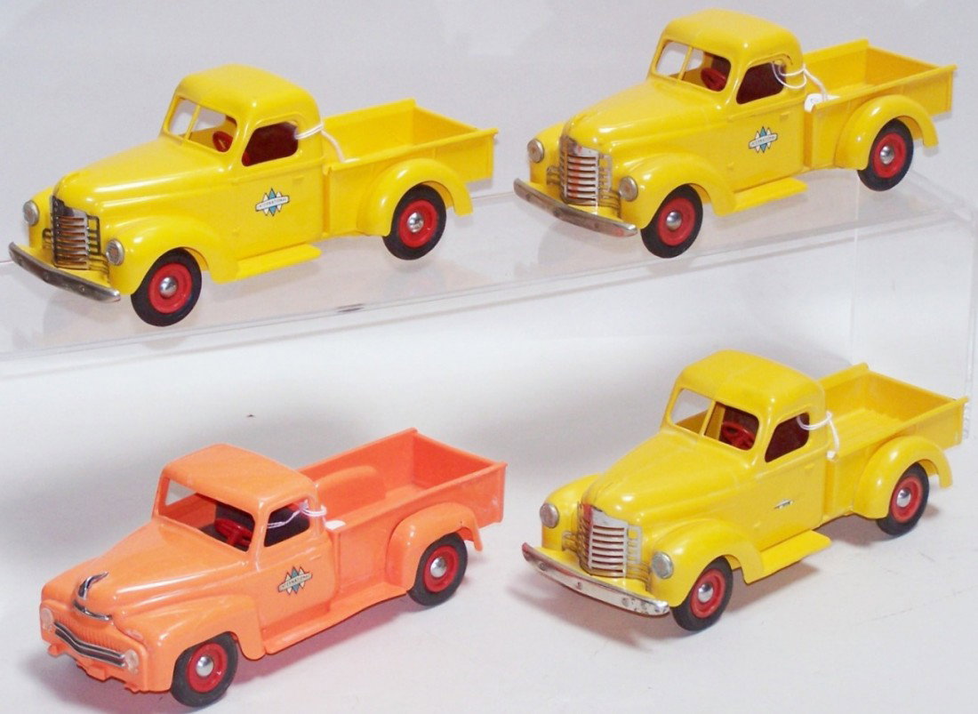 ***4 DEALER PROMO TRUCKS: Three yellow 1947 International Harvester pickup trucks with red wheels and a 1950/1951 orange International Harvester pickup truck with red wheels, all approximately 1/25 scale.