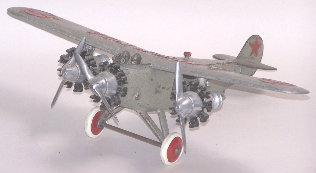 ***HUBLEY AMERICA TOY AIRPLANE: Tri-motor airplane with aluminum wing and cast iron body, having red front wheels with white tires, approximate wingspan 17'', length 14''.
