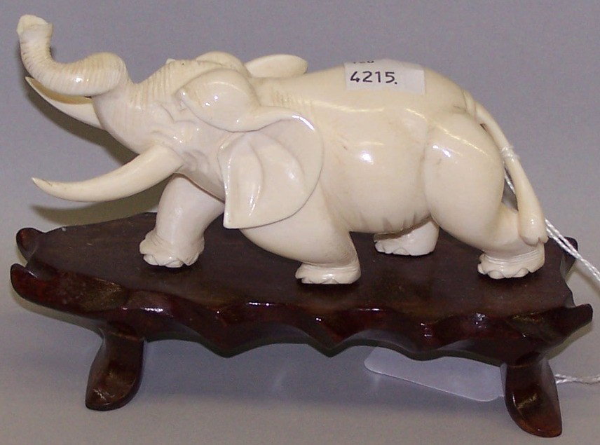 ***CHINESE CARVED IVORY ELEPHANT: Approximate height 3'', length 6'', width 2'', raised on hardwood stand. Note: Items containing ivory will only be shipped domestically.