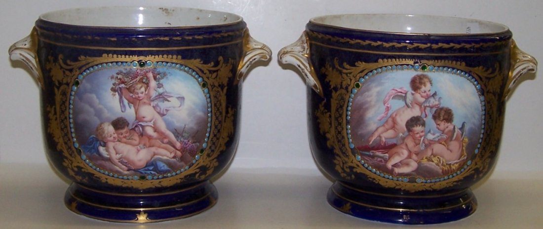 ***PAIR OF SEVRES STYLE PORCELAIN CACHEPOTS: Each having hand painted panel decoration depicting cupids in landscape, further enhanced with turquoise beadwork and gilt highlight against blue ground, approximate height 7''.