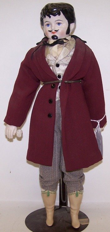 ***CHINA HEAD MALE DOLL: Having painted blue eyes, closed mouth, molded hair, sideburns, moustache and beard, cloth body with china hands and lower legs with molded boots, along with bisque smoking pipe, unmarked, approximate