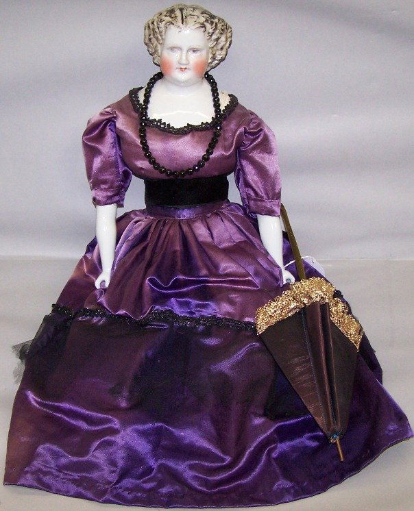 ***CHINA HEAD DOLL: Having painted eyes, closed mouth, flat top style head with molded and painted hair, cloth body with china lower arms and legs with molded and painted boots, unmarked, approximate height 23''.