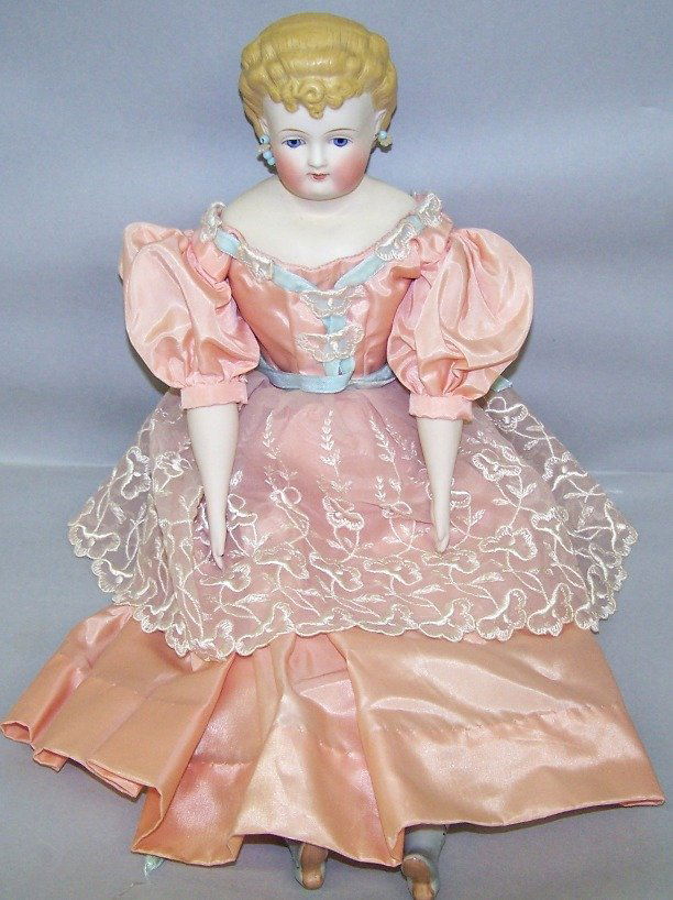 PARIAN WARE HEAD DOLL: Having painted blue eyes, closed mouth, molded blond hair, pierced ears with earrings, cloth body with Parian arms and lower legs with molded blue boots, unmarked, approximate height 18''.