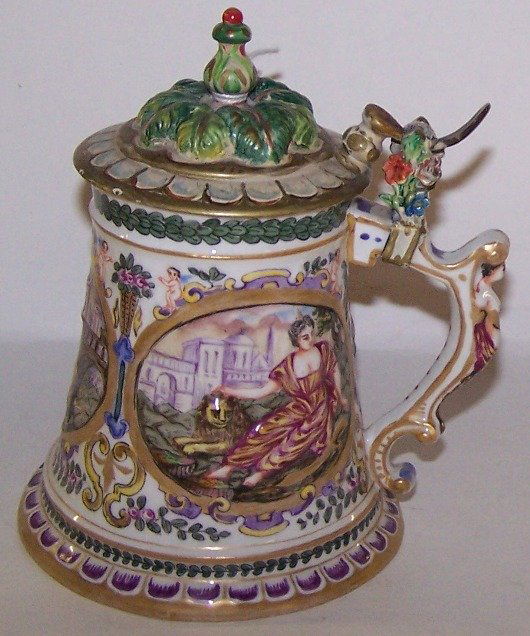 ***CAPODIMONTE STEIN: Having relief decoration depicting classical beauty with lion and reclining young man leaning on skull, having female term figure handle and floral decoration.