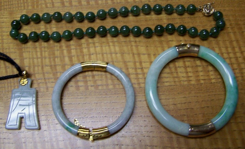 ***FOUR PIECES OF JADE JEWELRY: Comprising 2 bangle bracelets with gold mounts, a pendant with gold mount and a green jade bead necklace comprised of beads measuring 9.2 mm, approximate length 16'' and fitted with a 14K yellow gold 