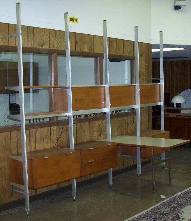 ***HERMAN MILLER WALL UNIT: Designed by George Elliot, walnut and polished metal in four sections with attached desk, fitted with sliding doors and drawers, approximate height 103'', width 129'', depth 53''.