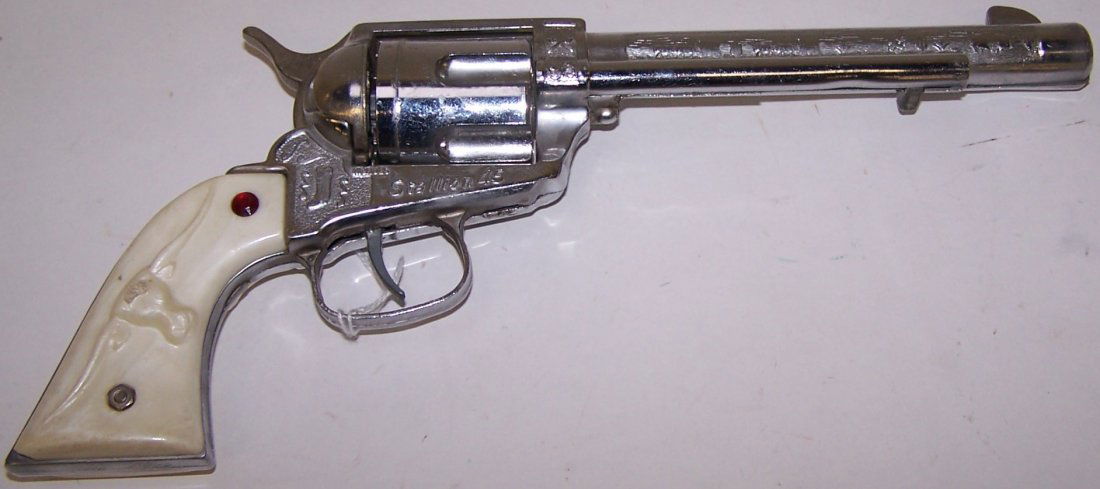 *NICHOLS STALLION 45 CAP GUN: Having embossed scene of wagon train on barrel, embossed stallion on white grips, embossed Nichols Stallion 45 under cylinder, cylinder rotates when trigger is pulled, approximately 12" long.