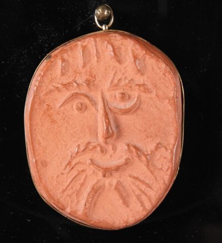 PICASSO, PABLO: (1881-1973 Spanish) Madoura red clay pendant impressed with face in yellow gold setting, stamped verso "Medoura Empreinte Originale De Picasso". marked 82/500, gold is stamped 18K, approximate size 2 