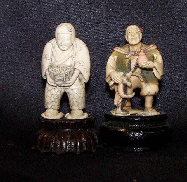 2 CARVED IVORY NETSUKES: Man with basket and man with monkey, both attached to wood stand, approximate height with stand 3". Note: Items containing ivory will only be shipped domestically and cannot be shipped to California.