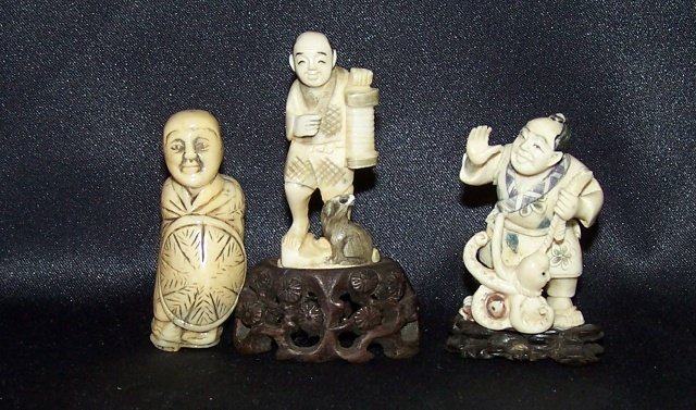 3 CARVED IVORY NETSUKES: Man with octopus and fish, man with lantern and animals, and man covered with tortoise shell, approximate height with stand 2 1/4", 3", and 2 1/4". Note: Items containing ivory will only be shipped do