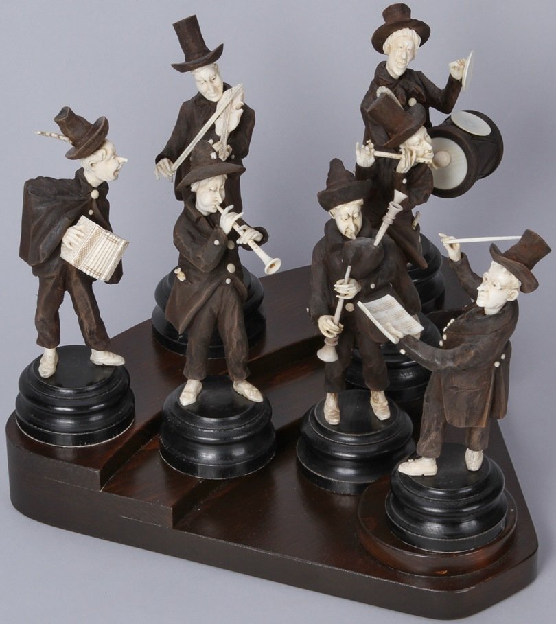 *CARVED WOOD AND IVORY FIGURAL ORCHESTRA SET: Drum and cymbal player, violin player, accordion player, flute player, bagpipe player, oboe player, and conductor, all resting on triangular 3-tiered wood base, each figure mounted to individual wood