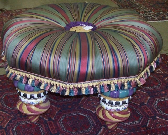 MACKENZIE-CHILDS TUFFET: The hexagonal form having silk multicolored upholstery raised on pottery legs decorated with pastel colors, approximate height 19", width 31".