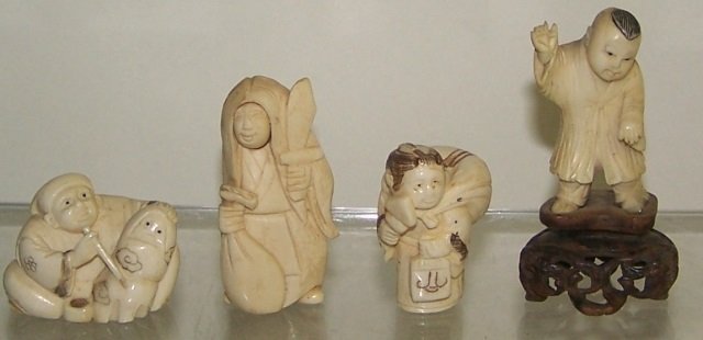 4 CARVED IVORY NETSUKES: Man smoking pipe, young boy, man with sword with revolving face, etc., 2 are signed, approximate height of tallest 2". Note: Items containing ivory will only be shipped domestically and cannot be ship