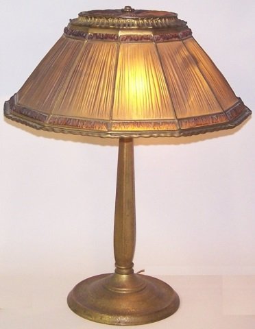 *TIFFANY STUDIOS GILT BRONZE & GLASS LAMP: Linen fold pattern, having 12 linen fold panels within borders of crinkled glass panels, surmounted by a matching linen fold panel glass inset cap with floral finial over a spreading stem with three s