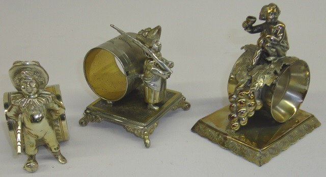 *3 VICTORIAN FIGURAL NAPKIN RING HOLDERS: 1 depicting young boy, 1 grape clusters, 1 young girl with rifle.